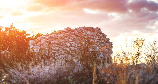 Mur d'une maison en ruine sur fond de nuages sombres pendant le coucher du soleil_