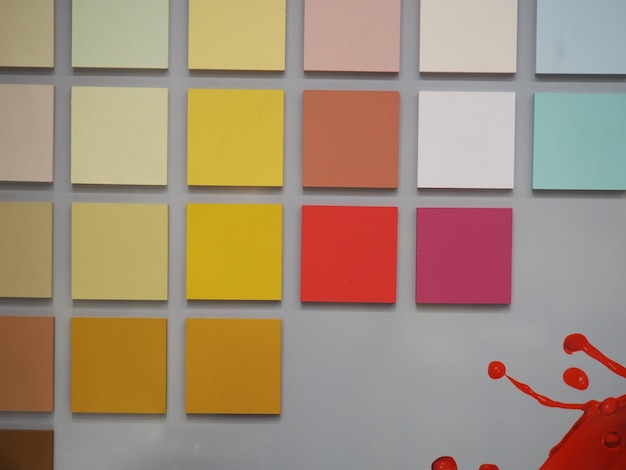 Photo un mur avec de nombreux carrés de couleurs différentes et un objet rouge en arrière-plan.