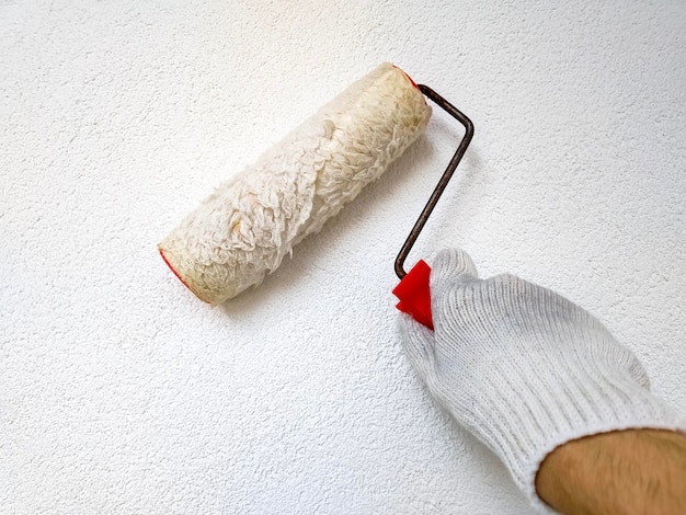 Mur de peinture à la main masculine avec rouleau à peinture Rénovation avec peinture de couleur blanche