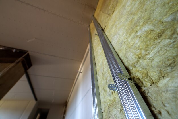 Photo mur d'une pièce en cours de rénovation avec isolation en laine de roche minérale et ossature métallique préparée pour plaques de plâtre.