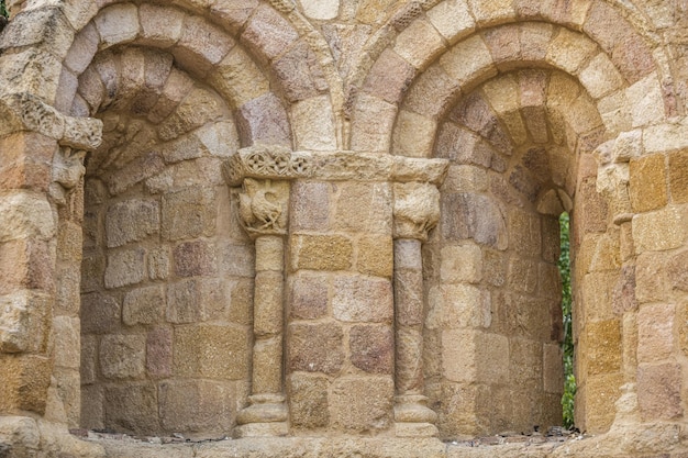 Mur en pierre d'une ancienne église romane à deux arches et ses fenêtres