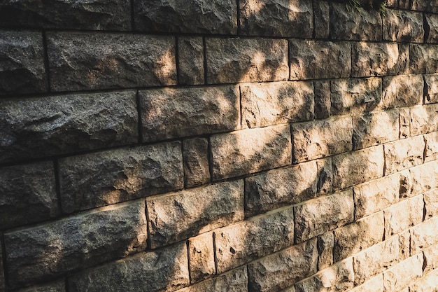 Mur de pierre de fond avec des taches de soleil, de lumière et d'ombre, lièvres solaires, soleil de mur de pierre