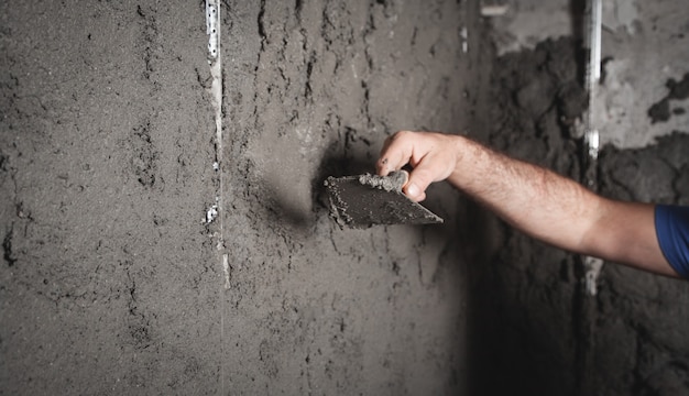 Mur de plâtrage de travailleur. Les travaux de construction