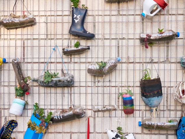 Mur rempli de pots de fleurs fabriqués avec des bouteilles en plastique, fabriqués par des écoliers, à l'extérieur