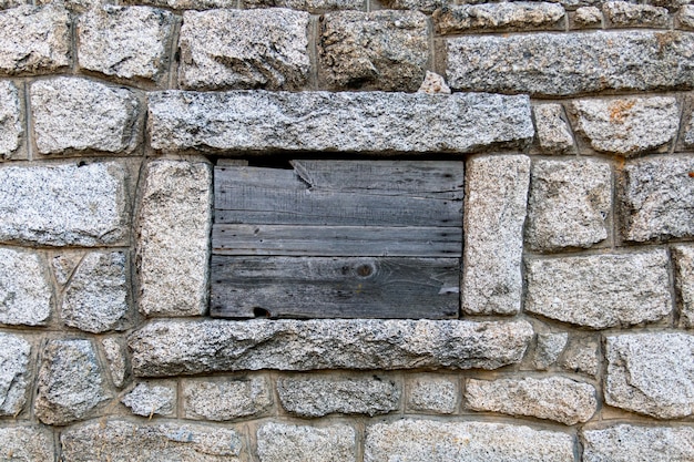 Mur de roche et fenêtre fermée recouverte de palettes en bois Fenêtres Boardedup