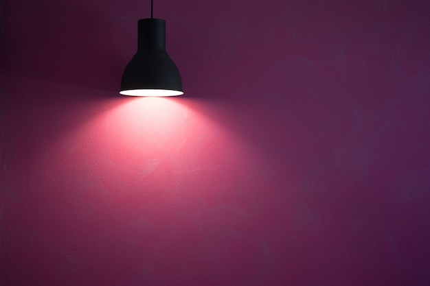 Mur rouge illuminé par une lampe à cône élégante noire vintage.