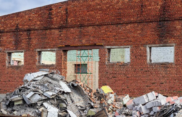 Le mur en ruine d'une vieille maison en brique rouge avec des fenêtres et pas de toit