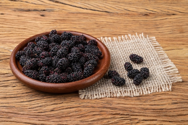 Mûres dans une assiette sur table en bois.