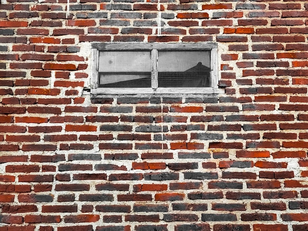 Photo des murs en briques brunes et des fenêtres en bois au centre