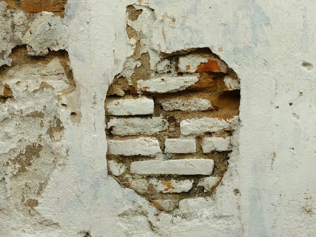 murs de ciment blanc qui se décollent de la surface. briques entre les murs brisés. maison abandonnée.