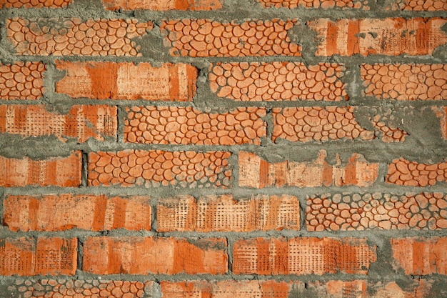 Les murs sont des briques d'argile rouge texturées avec un motif. Contexte d'une nouvelle maison en brique avec du ciment.