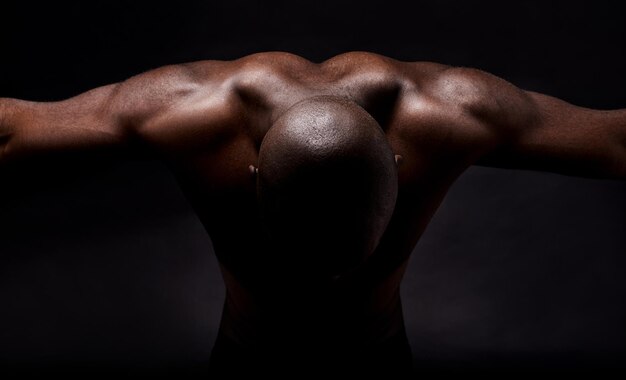 Muscles purs et masculinité Prise de vue en studio d'un homme afro-américain musclé se penchant en avant