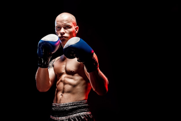 Musculaire muay thai fighter poinçonnage dans l'obscurité
