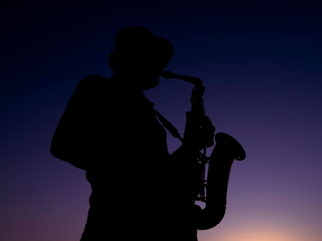 Un musicien jouant du saxophone au coucher du soleil