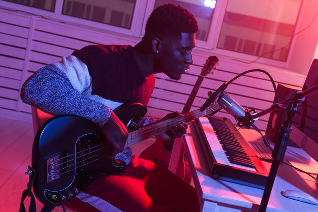 Musicien professionnel afro-américain enregistrant la guitare basse en studio numérique à la maison, musique