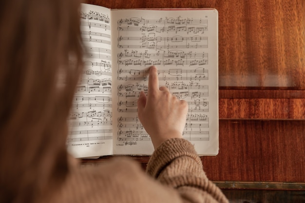 Une musicienne enseigne une pièce assise devant les notes du piano.