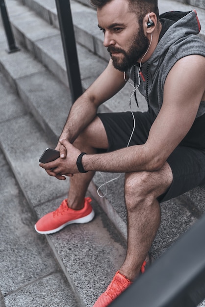 La musique dans son coeur. Beau jeune homme en vêtements de sport écoutant de la musique