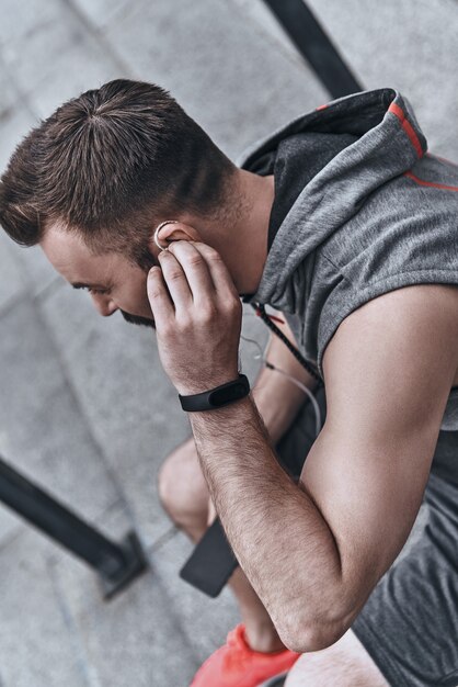 la musique le motive toujours. beau jeune homme en vêtements de sport ajustant ses écouteurs