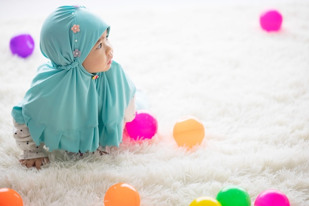 Muslim Baby joue avec des jouets colorés dans le salon.