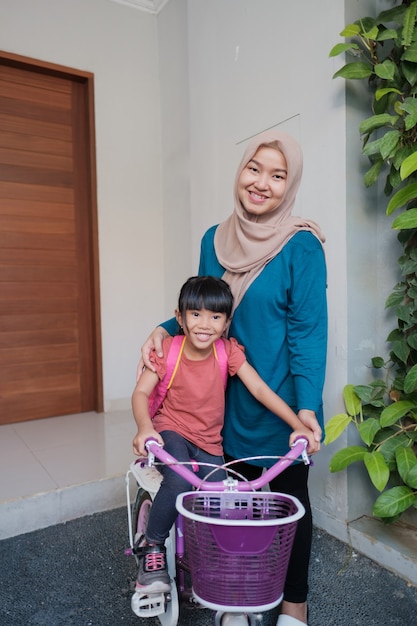 Musulmane et sa fille se préparent à aller à l'école le matin en faisant du vélo