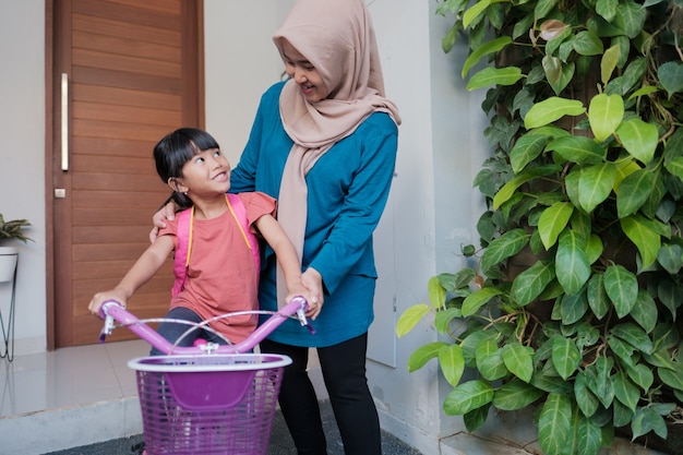 Musulmane et sa fille se préparent à aller à l'école le matin en faisant du vélo