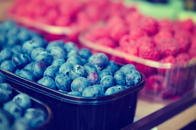 Myrtille et framboise fraîches dans une boîte en plastique au marché des aliments locaux sains dans un style hipster vintage