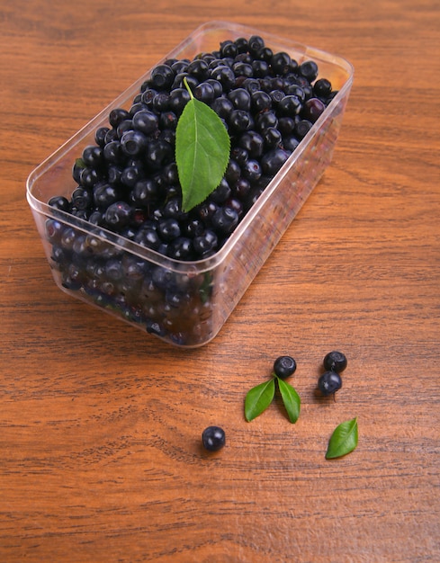 Myrtilles, cassis avec feuille en boîte sur l'espace en bois