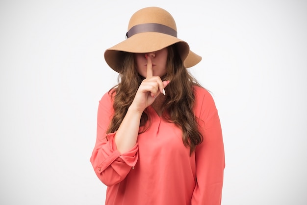 Mysterious girl in hat geste silence signe tenant l'index sur les lèvres