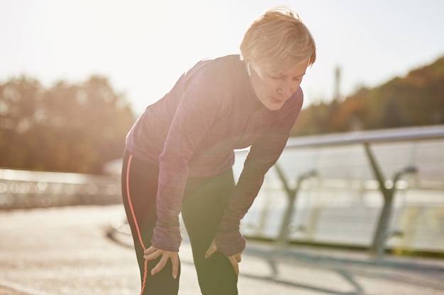 Photo n'en faites pas trop une femme mature active en tenue de sport qui a l'air fatiguée et épuisée de se reposer après