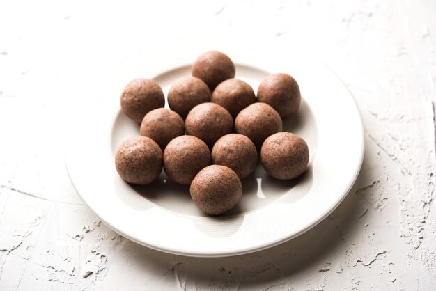 Nachni laddu ou Ragi laddoo ou boules faites avec du millet, du sucre et du ghee. C'est un aliment sain de l'Inde. Servi dans un bol ou une assiette avec du cru entier et de la poudre. Mise au point sélective