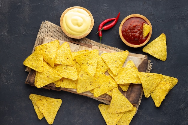 Nachos de chips de maïs mexicain avec sauces sur fond sombre. Vue de dessus.