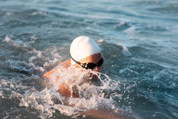 Photo nageur masculin avec bonnet et lunettes nageant dans l'océan