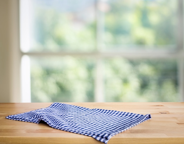 Nappe à carreaux bleu sur bois avec bokeh vert flou de la fenêtre