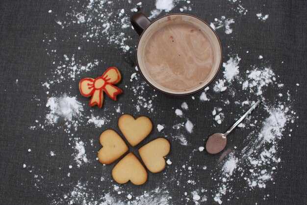 Photo une nappe noire avec de la farine une tasse de biscuits au chocolat chaud et une cuillère avec du cacao noël
