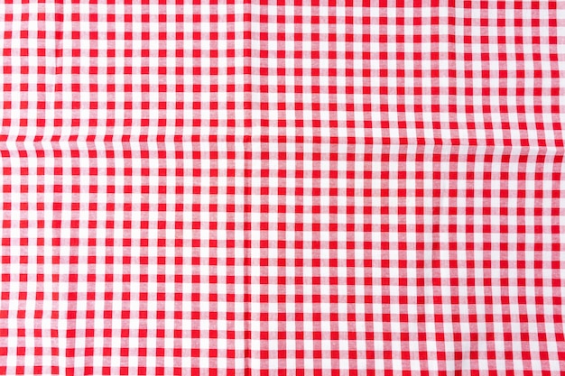 Une nappe de salle à manger froissée avec un motif à carreaux blanc et rouge est l'arrière-plan Vue de dessus pour la conception de menus alimentaires Utilisée pour couvrir la table à manger pour éviter les taches et faciliter le nettoyage de la table