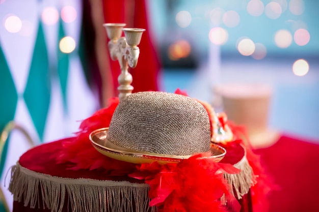 Sur la nappe de velours se trouve un chapeau de théâtre doré avec des plumes et un chandelier