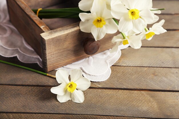 Narcisse frais dans la poitrine sur fond de bois