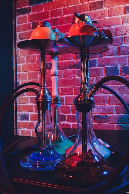 Photo narguilé chicha rouge avec de la fumée et des étincelles rouges sur fond d'art de brique de table en bois concept de chicha