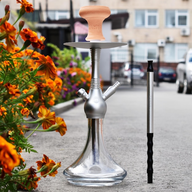 Narguilé avec flacon en verre et bol en terre cuite avec de la fumée sur fond de rue