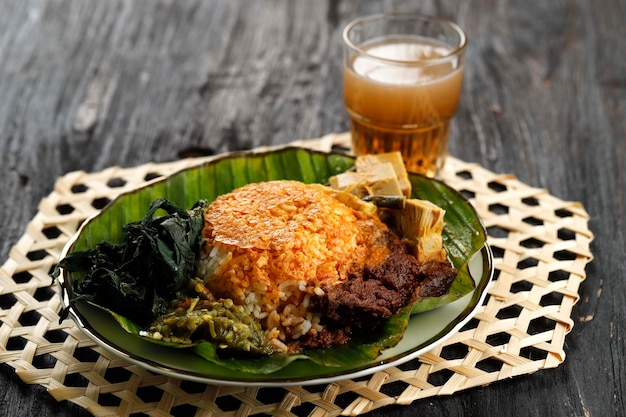 Nasi Padang ou Padang Rice est un célèbre aliment traditionnel d'Indonésie Riz avec des feuilles de manioc Rendang de boeuf et de la pâte de piment vert sur une table en bois