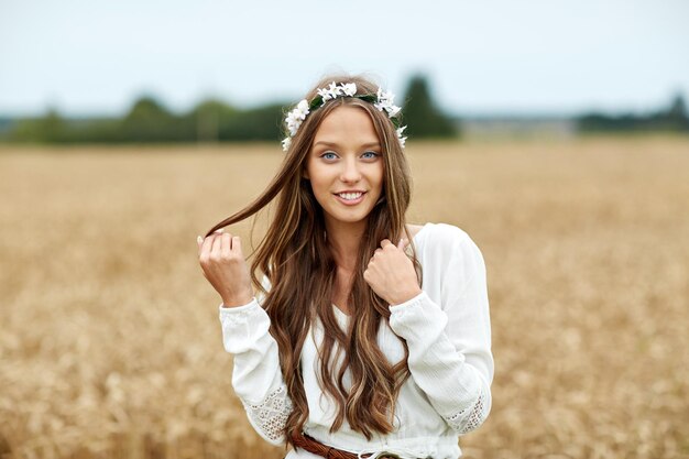 nature, été, culture des jeunes et concept de personnes - jeune femme hippie souriante portant une couronne de fleurs sur un champ de céréales