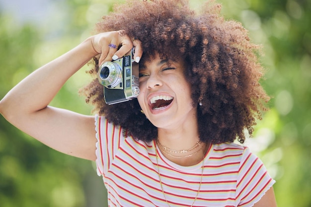 Nature femme afro et noire avec appareil photo prenant une photo heureuse avec une fille hipster africaine de style rétro avec le sourire dans le parc à l'aide d'un équipement de photographe vintage pour capturer le moment