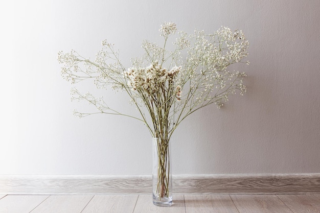 Une nature morte aérée avec des fleurs séchées dans un vase