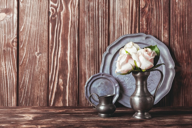 Nature morte avec assiette antique et fleurs en pot d'étain