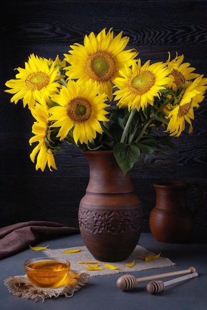 Nature morte au bouquet de tournesols et de miel sur une table grise