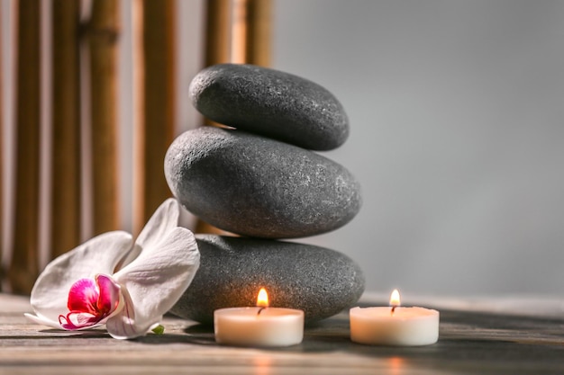 Nature morte au spa avec des bougies de galets et une fleur d'orchidée sur fond gris