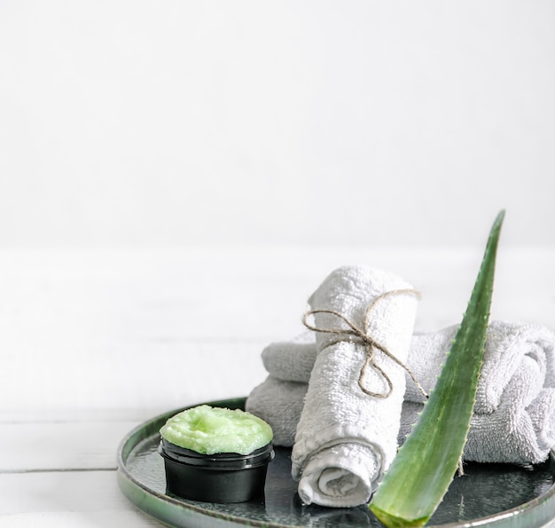 Nature morte au spa avec des soins de la peau bio, des feuilles d'aloès fraîches et des serviettes