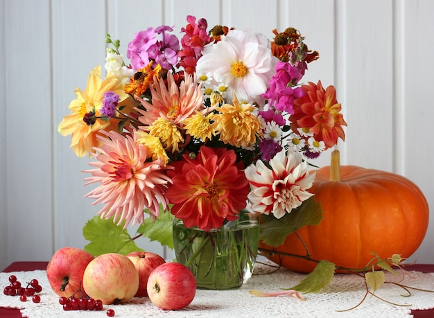 Nature morte d'automne avec un bouquet de fleurs, de pommes et de citrouille sur la table. récolte, abondance.