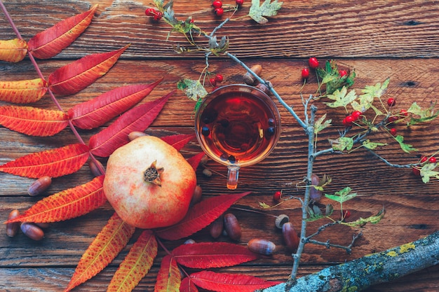 Nature morte d&#39;automne de feuilles colorées, une tasse de thé, de grenade, de glands et une branche