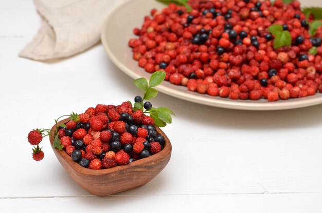 Nature morte aux baies sauvages sur la table fraises et myrtilles dans un bol